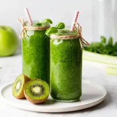 Dwa zielone koktajle w słoikach z kiwi, jabłkami i słomkami.